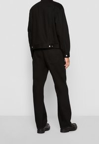 Svart denimjacka och matchande byxor med en avslappnad passform. Minimalistisk design med silverdetaljer och en slät yta.