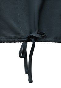 Schwarzer Stoff mit einer glatten Textur, mit einem gerafften Design am Saum und einem gebundenen Verschluss mit dünnen Schnüren. Sichtbare Nähdetails.