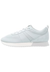 Chaussure de sport bleu clair en mesh et matériaux synthétiques, dotée d'un design à lacets, d'accents texturés et d'une semelle blanche dentelée.