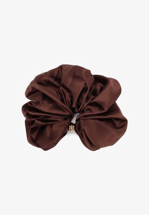 Grote donkergroene satijnen scrunchie met geplooide stof en een kleine goudkleurige decoratieve ring in het midden, op een witte achtergrond.