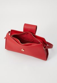 Rode leren handtas met een driehoekige vorm, voorzien van een ritssluiting, binnenzakken en een goudkleurige drukknoopaccent.