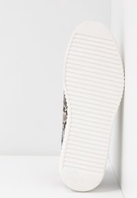 Sneaker with a textured black and white snake print upper, flat white rubber sole, and ridged pattern for traction. Size 37 marked.