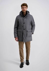 Grau gepolsterte Parka-Jacke mit Kapuze, ausgestattet mit Knopfschlüssen, vier Fronttaschen und einer glatten Textur, kombiniert mit beigen Hosen und schwarzen Stiefeln.