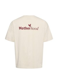 Beige t-shirt met de tekst "Moederschap" in rood en bruin, met een klein hartje boven de "h" op de achterkant in het midden.