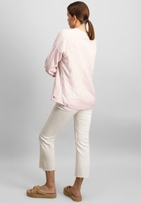 Šviesiai rožinė lininė palaidinė su ilgomis pūstomis rankovėmis, derinama su off-white trumpomis kelnėmis ir tan pynėmis šlepetėmis. Minimalistinis dizainas ir laisvas siluetas.