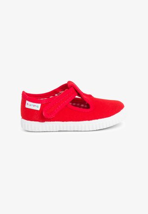 Rode canvas schoen met een klittenbandsluiting, witte rubberen zool en een cirkelvormig textuurpatroon. Heeft een geruite voering en een merketiket.