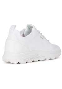 Vit sneaker med övre del i stickad textil, gummisula och design med vågig yttersula. Har en dragtab och snörning för en säker passform.