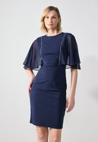 Robe de marine avec des manches flottantes en tissu léger. Dotée d'un corsage ajusté et d'un subtil accent perlé le long de l'encolure.