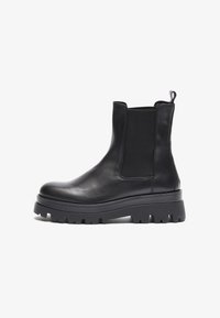 Botas de cuero negro hasta el tobillo con paneles laterales elásticos, punta redonda y una suela de goma gruesa con profundos surcos para mayor tracción.