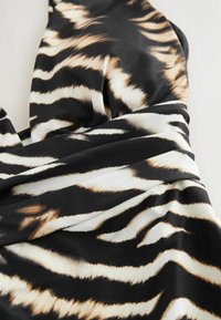 Black fabric with white and brown tiger stripes, featuring a smooth texture and draped design, layered in soft folds.