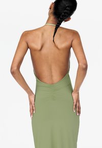 Rückansicht eines enganliegenden, olivgrünen Kleides mit tiefem V-Ausschnitt, Raffung und Nackenband-Design. Glatte Textur und elastischer Stoff.
