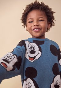 Maglione lavorato a maglia in blu con grandi facce di Topolino in stile cartone animato e pois neri. Collo rotondo e tessuto testurizzato.