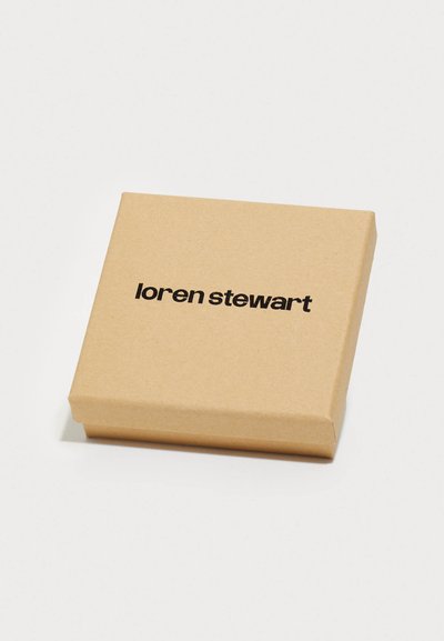 Smeđi kartonski kutija s glatkom teksturom, s crnim natpisom "loren stewart" otisnutim na gornjoj površini. Kvadratnog oblika, minimalističkog dizajna.