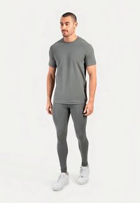 Grå tætsiddende t-shirt og leggings lavet af elastisk stof, kombineret med hvide sneakers; glat tekstur med et minimalistisk design.