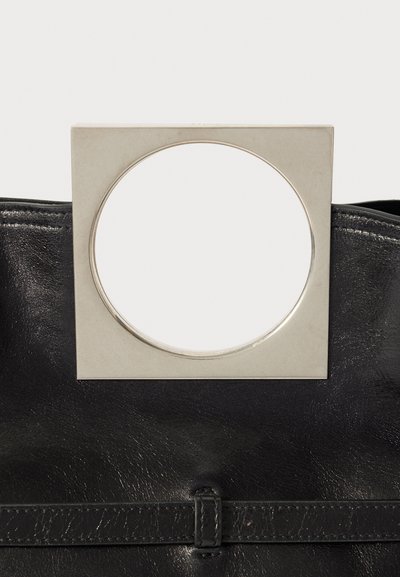 Black leather handbag featuring a square metallic handle with a circular cutout. Smooth texture with minimal embellishments and a subtle sheen.