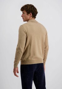 Beiger gestrickter Pullover mit langen Ärmeln und geripptem Saum. Verfügt über einen klassischen Kragen und eine strukturierte Oberfläche, kombiniert mit dunklen Cordhosen.