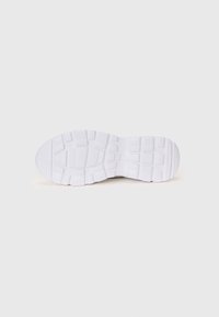 White athletic shoe sole, featuring a textured rubber surface with grooves and patterned indentations for traction.