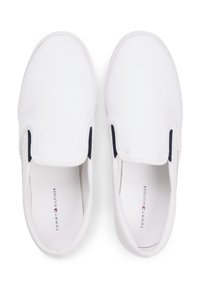 Paire de chaussures casual blanches sans lacets avec panneaux latéraux élastiques et logo Tommy Hilfiger sur les semelles intérieures, vue de dessus.
