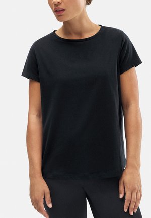 Camiseta negra de manga corta en tejido suave con cuello redondo y corte relajado, combinada con leggings negros ajustados.