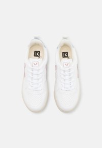 Vita sneakers med perforerat tårum, rosa och blå accenter samt vita snören. Slät material med gummisula och logotyptryck.