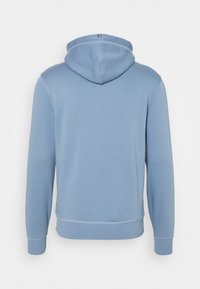 Sudadera de algodón en azul claro, con capucha ajustable, puños acanalados y un dobladillo recto con costuras en contraste. Se muestra vista trasera.