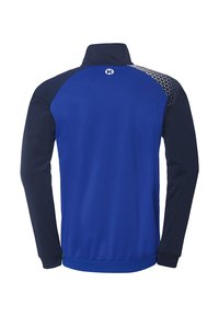 Blå sportsjakke med høj krave, marineblå ærmer og trekantede mønsterdetaljer på skuldrene. Har en blød tekstur og elastiske manchetter.