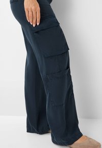 Navyblauwe wijde pijpen gemaakt van lichtgewicht stof, met meerdere grote zakken en een relaxte pasvorm, met een gladde textuur en eenvoudige naden.