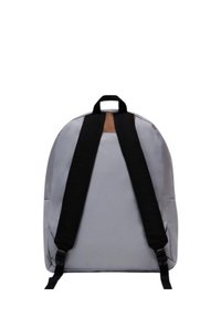 Zaino grigio con spallacci neri regolabili, dotato di una maniglia superiore e di un accento marrone sulla parte superiore. Texture liscia e design arrotondato.