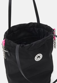 Sac seau noir en nylon avec des accents roses, quincaillerie en argent et un logo rond. Dispose de deux poignées et d'une fermeture à cordon. Intérieur texturé.