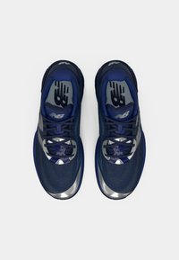 Baskets de sport bleu foncé avec partie supérieure en mesh, accents argentés métalliques, design texturé et fermeture à lacets. Semelle en caoutchouc antidérapante visible.