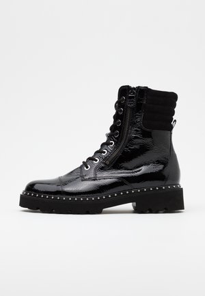 Bottes de combat en cuir verni noir avec semelle épaisse, fermeture éclair latérale, lacets et clous argentés le long du bord de la semelle. Tissu texturé en haut de la tige.