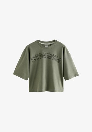 T-shirt en coton vert olive, à manches courtes, avec un col rond, portant "COPENHAGUE" en lettres noires grasses sur le devant.