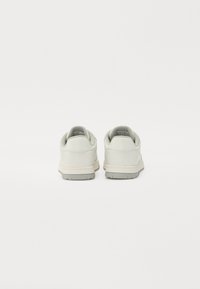 Light grey leather sneakers featuring a smooth texture, round toe, cushioned collar, and a durable rubber outsole with a subtle tread pattern.