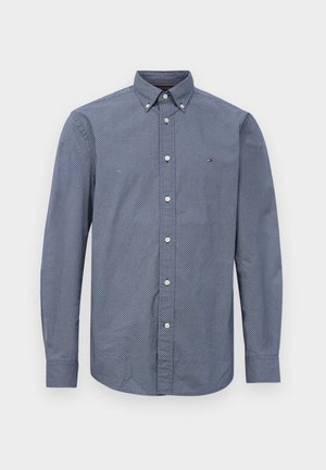 Chemise à manches longues pour homme, boutonnière, de couleur marine avec de petits motifs géométriques blancs, col boutonné et fermeture à boutons sur le devant.