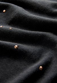 Zwarte stof met een gestructureerde textuur, voorzien van een gladde oppervlakte en verschillende kleine, metallic roségouden accenten verspreid over het materiaal.