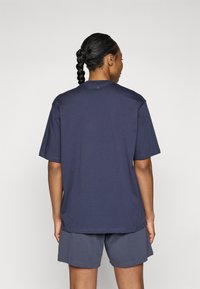 Navy blue cotton t-shirt with a relaxed fit, short sleeves, and a round neckline, paired with gray shorts. Minimalist design, no visible patterns.