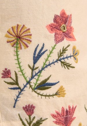 Broderie florală colorată cu ață roz, galbenă, albastră și verde pe țesătură bej, cu petale detaliate și tulpini cusute.