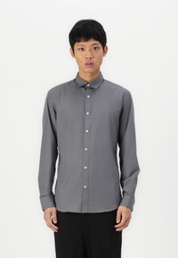 Camisa abotonada de manga larga en gris, con cuello punta, que presenta una textura de tela suave y botones blancos en el panel delantero.