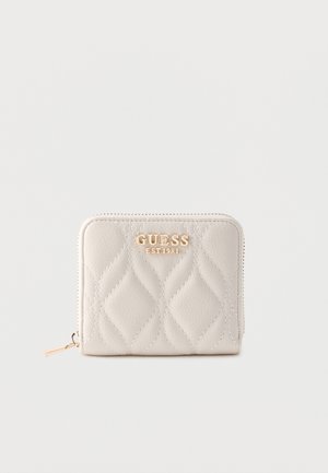 Pieni beige tikattu lompakko, jossa on kullanvärinen "GUESS EST 1981" -logo ja vetoketjullinen suljenta yksivärisellä taustalla.