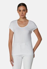 Witte t-shirt met korte mouwen en een ronde hals, gemaakt van zachte stof, met opgerolde mouwen en een ontspannen pasvorm. Katoene textuur, minimalistisch ontwerp.