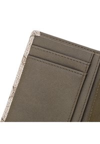 Acercamiento de la esquina de una cartera de cuero marrón que muestra dos espacios para tarjetas y un detallado de la costura en los bordes de tejido texturizado.