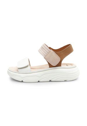 White and beige sandals with elasticized brown strap, cushioned sole, rounded shape, and textured rubber outsole for traction.