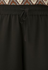 Black jogger pants with a textured surface, featuring an elastic waistband and drawstring. The fabric appears soft and lightweight.