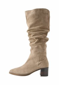 Knielange, slordige beige suède laars met een vierkante neus, gestructureerd oppervlak en een blokhak. Bevat subtiele stiksels langs de naden.