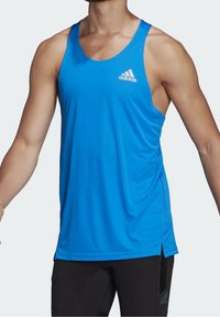 Débardeur de sport bleu en tissu léger. Il présente un col rond, une coupe slim et le logo Adidas sur la poitrine.