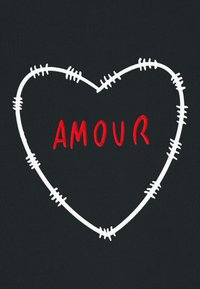 Juodas audinys su baltu siuvinėtu širdies kontūru ir išsibarsčiusiais siūlų akcentais, o centre užrašyta žodis "AMOUR" ryškiomis raudonomis raidėmis.