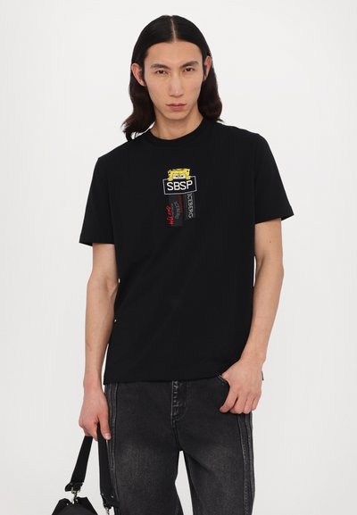 Sort t-shirt med rund halsudskæring, prydet med farverige grafiske prints, herunder "SBSP" og "ICEBERG" på forsiden. Korte ærmer, afslappet pasform.