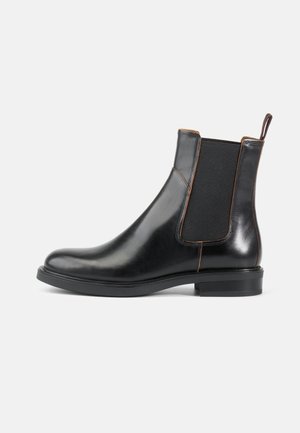Sorte skinn Chelsea boots med elastiske sidepaneler, avrundet tå og glatt overflate. Har en kort hel og en trekklo bak.