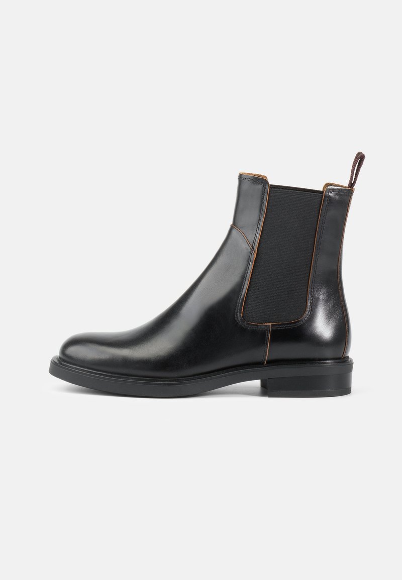 Botas Chelsea de cuero negro con paneles laterales elásticos, punta redondeada y acabado suave. Presenta un tacón corto y una lengüeta en la parte posterior.