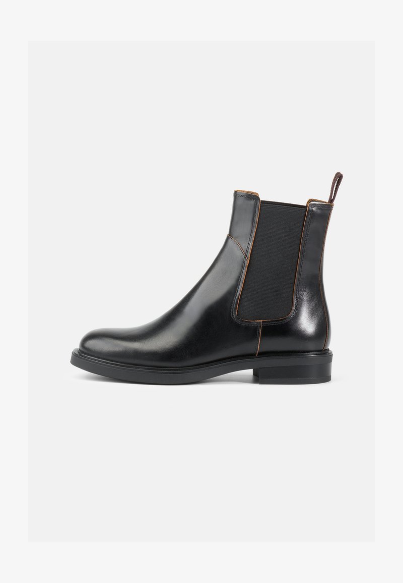 Botas Chelsea de cuero negro con paneles laterales elásticos, punta redondeada y acabado suave. Presenta un tacón corto y una lengüeta en la parte posterior.